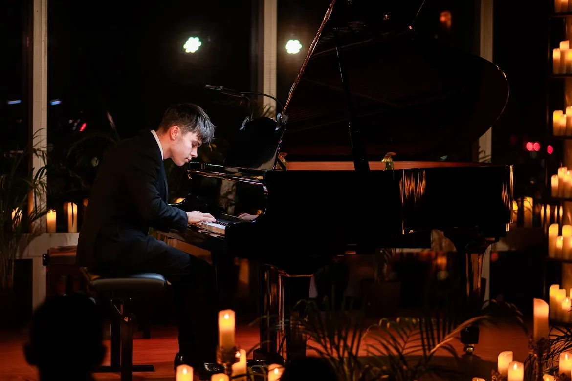 A FortepianArt pianist performing on a grand piano at a candlelit concert